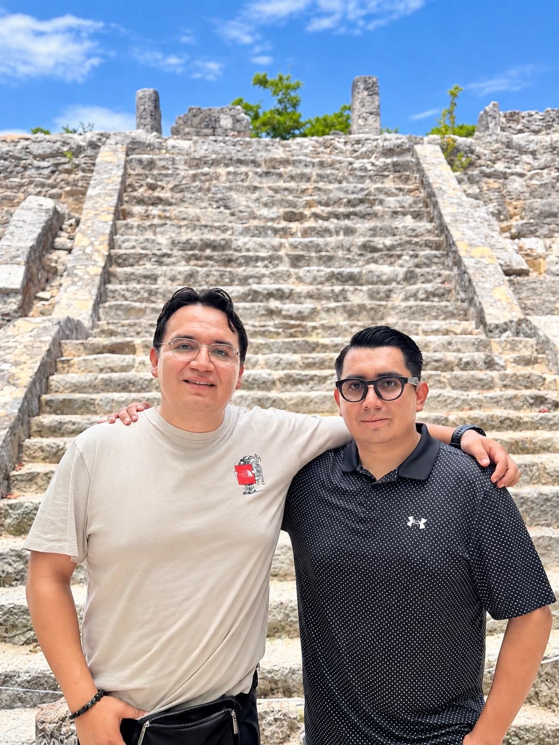 Hugo and Gabriel standing together in front of ancient stone pyramid steps in Mexico