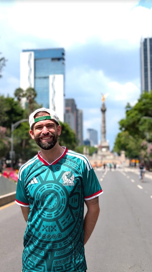 Josh in a Mexico national team jersey on Paseo de la Reforma, with the Angel of Independence behind him