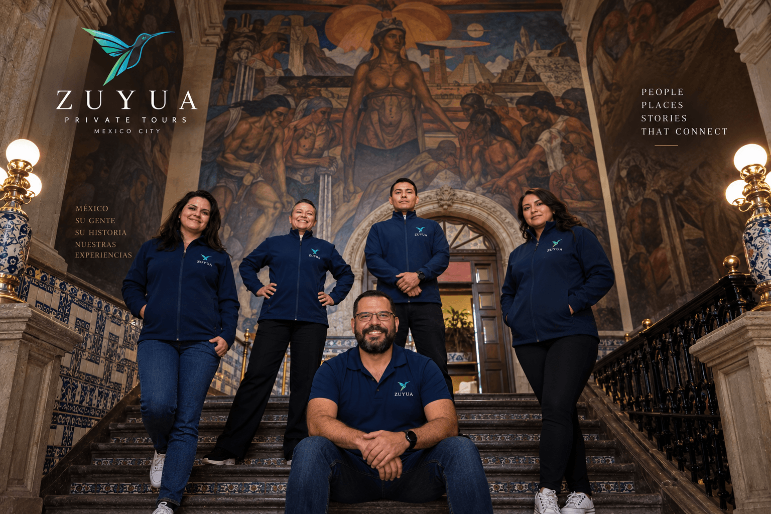 Roberto Quiñonez, founder of Zuyua Private Tours, seated on a grand staircase beneath a Mexican mural with his team of guides